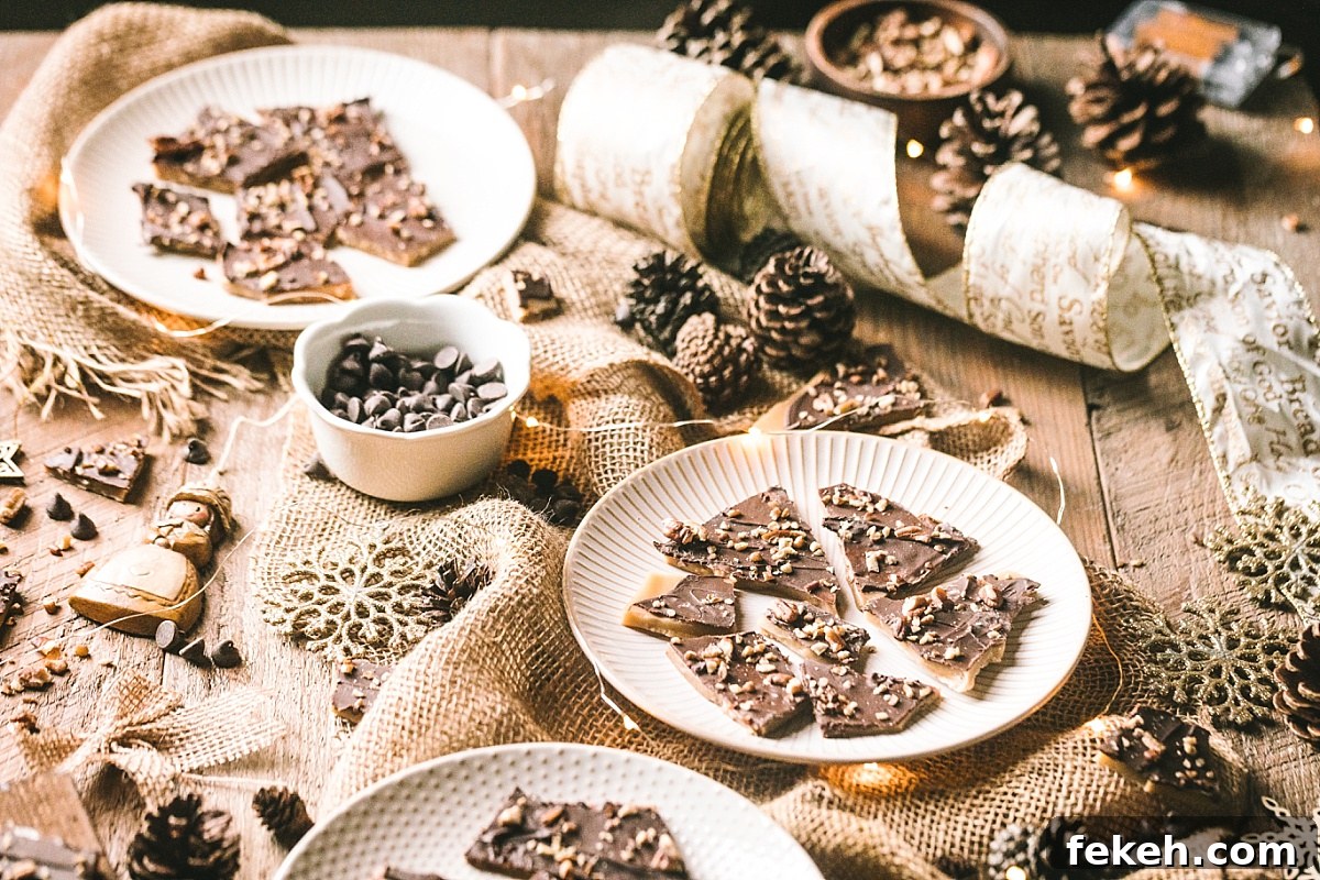 plate of almond and pecan amber covered butter toffee surrounded by bowl of semi-sweet chocolate chips, twinkle lights, and other rustic brown christmas decor