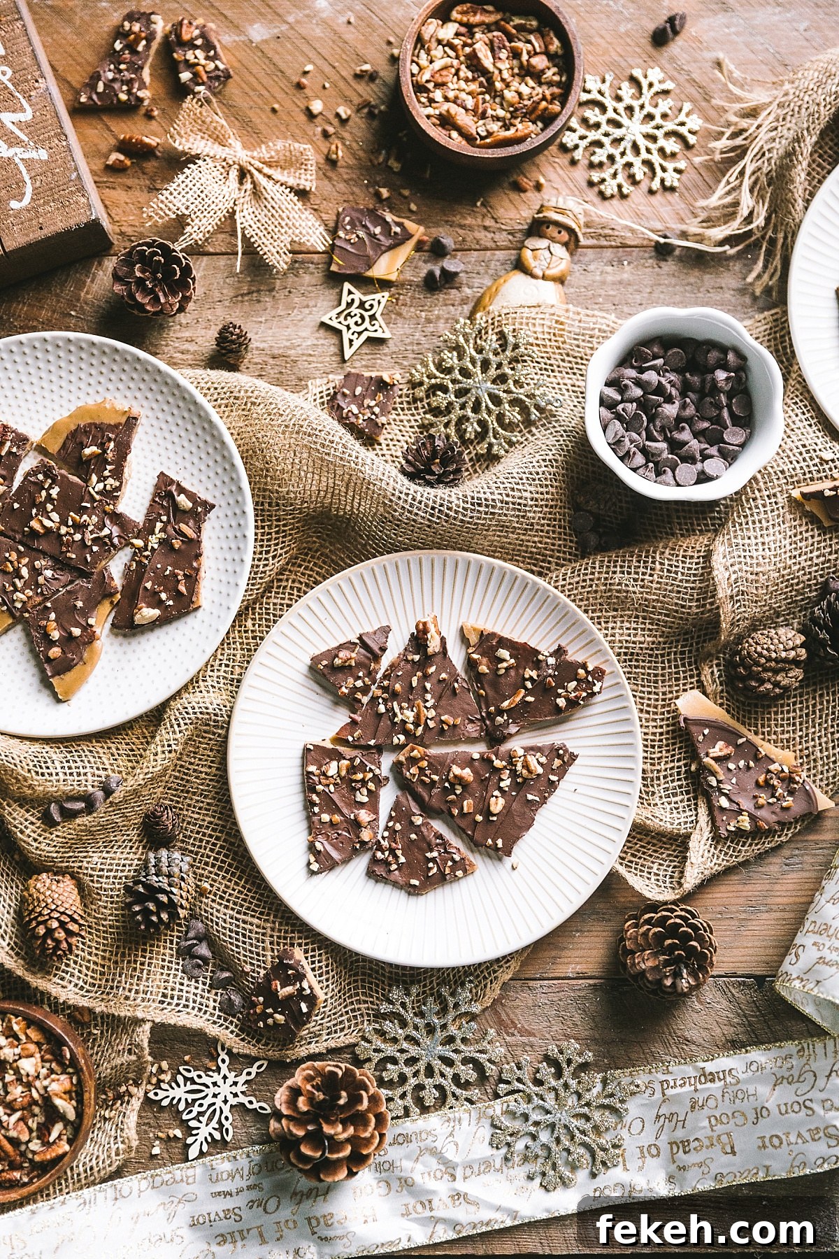 overhead shot of plates of golden English toffee with swirled chocolate and roasted pecans surrounded by a rustic baking scene with vintage gold and wooden Christmas ornaments