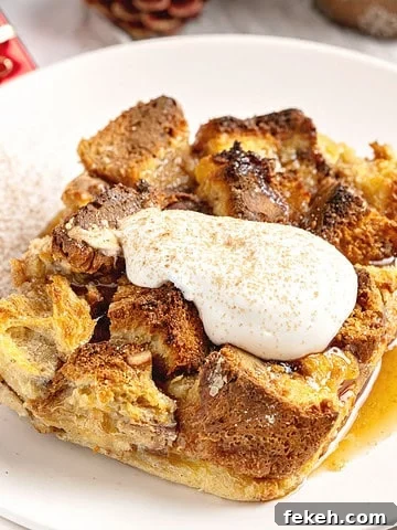 Serving of panettone bread pudding with cream and cinnamon. White plate.