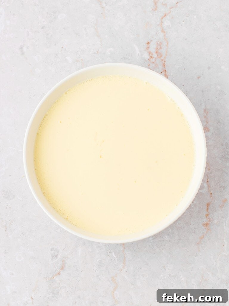 Custard binding sauce for bread pudding in a white bowl. Light gray background.