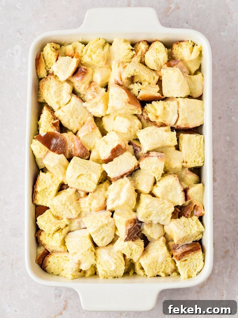 Soaked brioche bread cubes in a rectangular white dish. Light gray background.