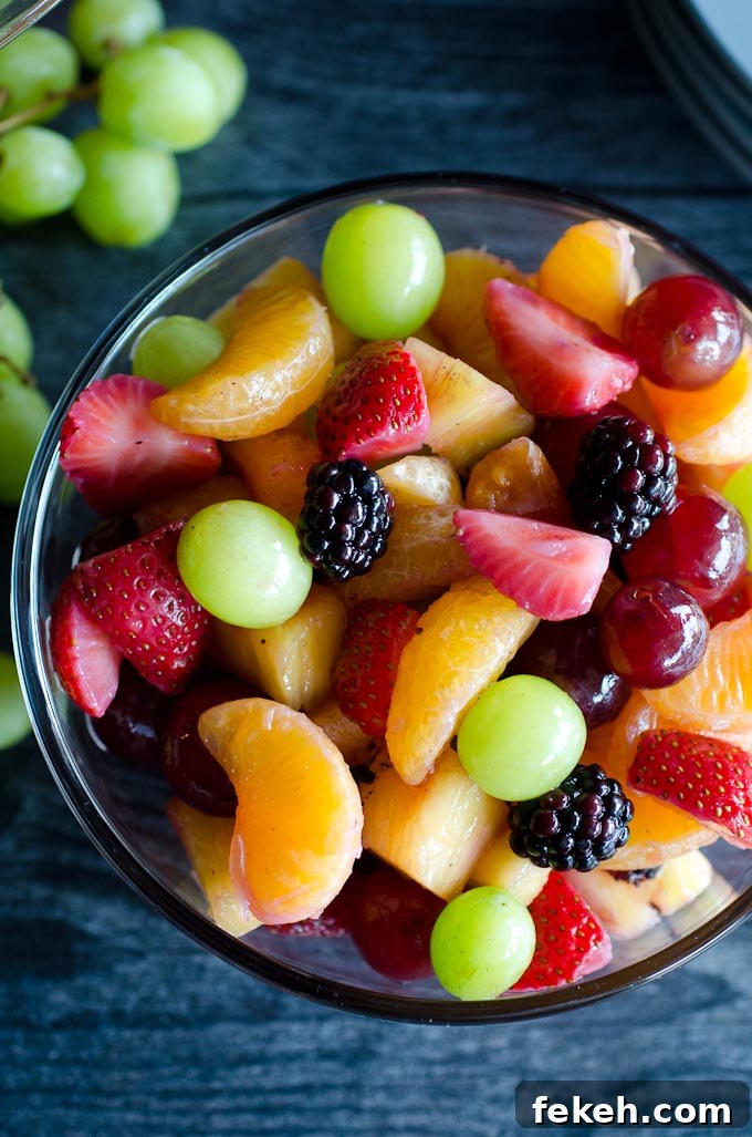 bowl of fruit with green grapes in background