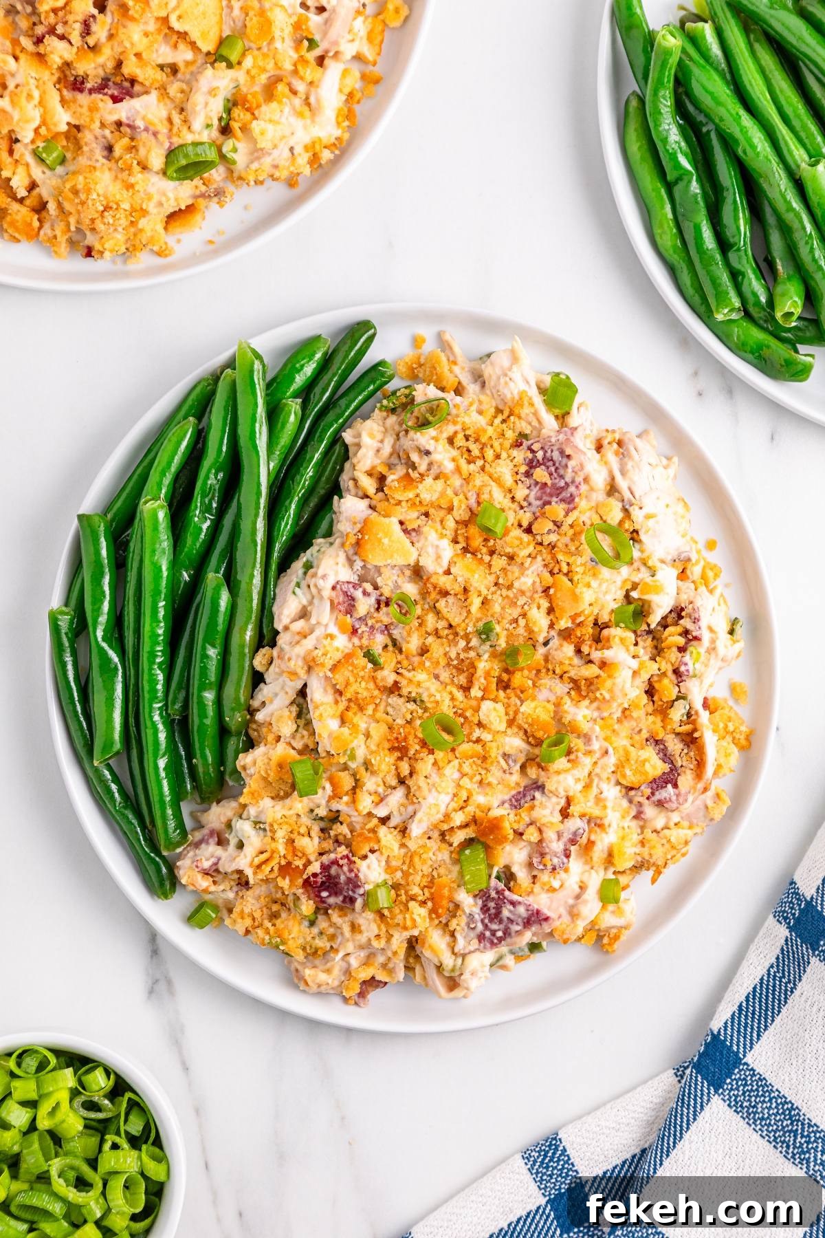 A plate with green beans and a creamy casserole topped with crushed crackers and green onions.
