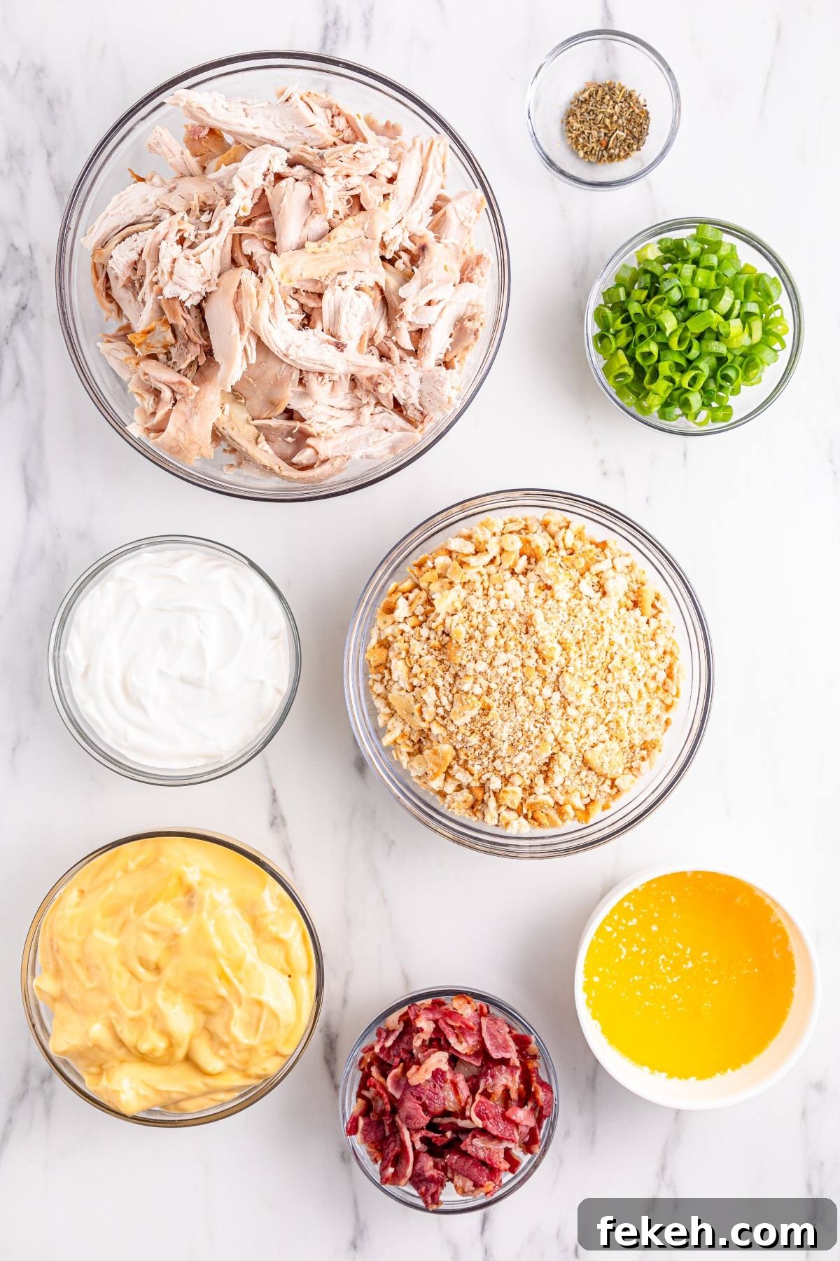 Seven bowls with shredded chicken, sour cream, crushed crackers, melted butter, cheese sauce, bacon, and green onions.