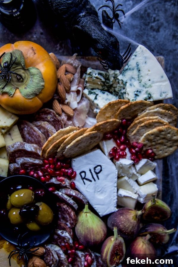 Close up of Halloween charcuterie board showing a gourd, meats, cheeses, crackers and pomegranate seeds.