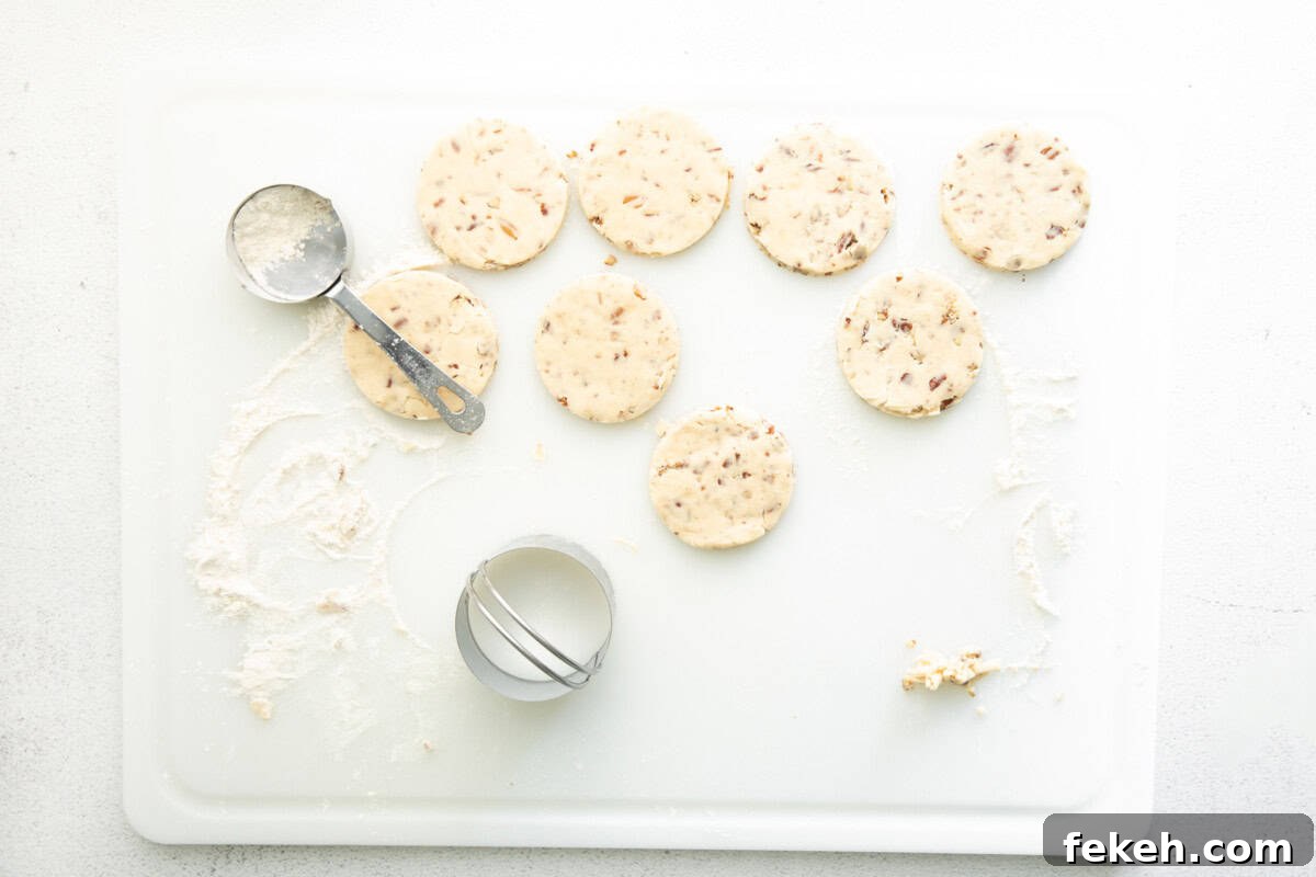 cut out pecan shortbread cookies on a floured cutting board.