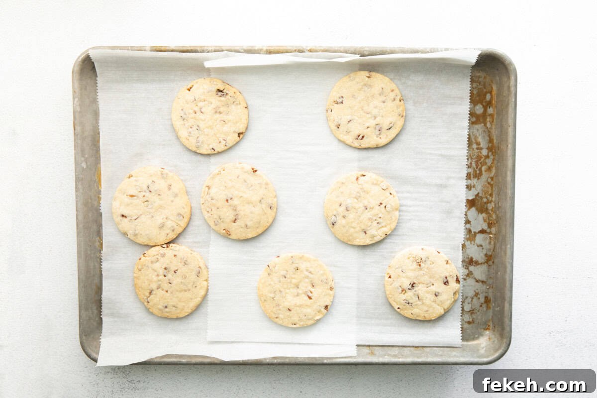 freshly baked pecan shortbread cookies on a lined baking sheet.