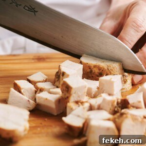 Slicing chicken into cubes.