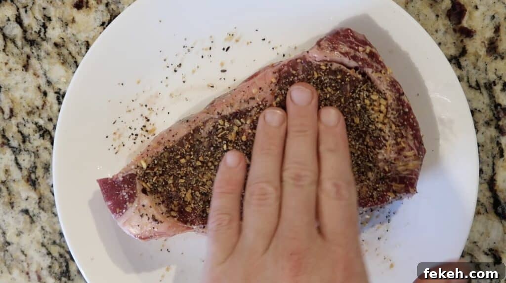 Hands rubbing seasoning into steak