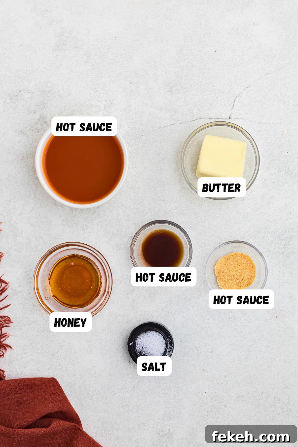 Ingredients needed to make buffalo sauce, measured into small bowls, on a white marble table. 