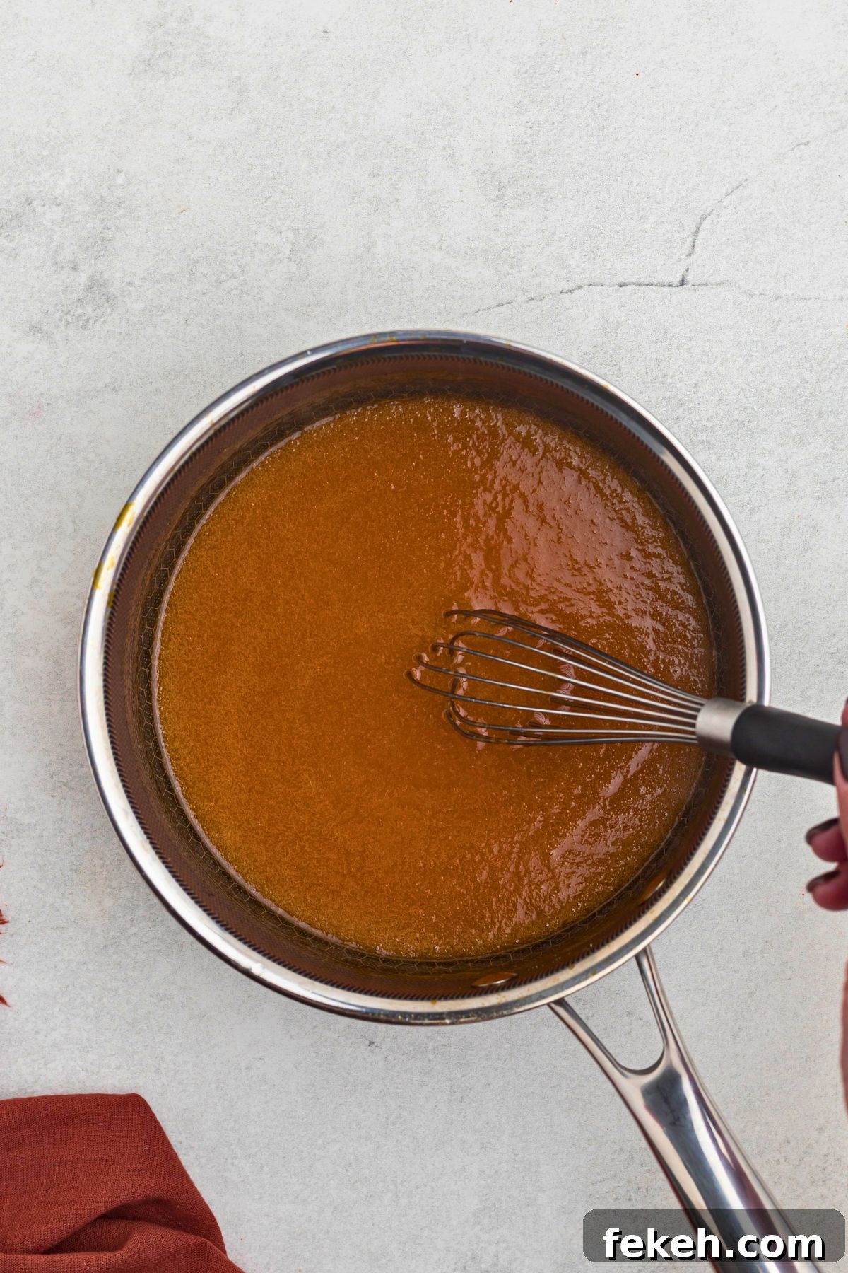 Creamy, buttery, orange sauce being whisked together in a saucepan. 